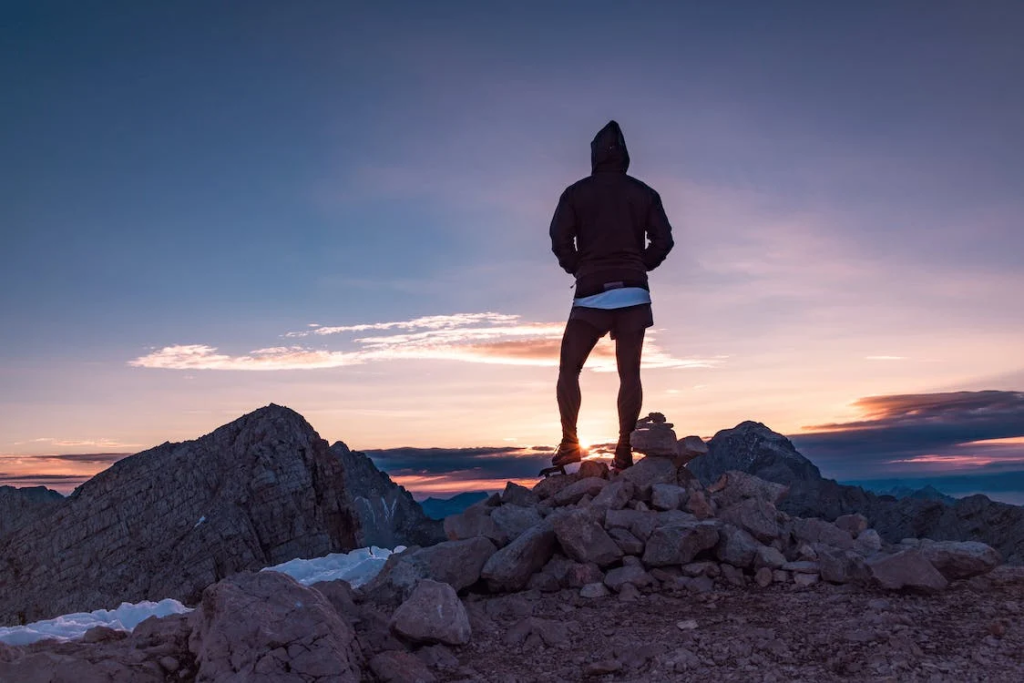 An image of a man standing rocks during the golden hour