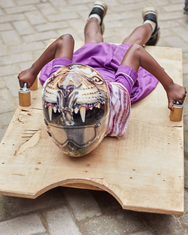 A child in Akwasi’s helmet playing with a skeleton board