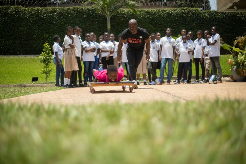 A child trying skeleton racing with Akwasi Frimpong