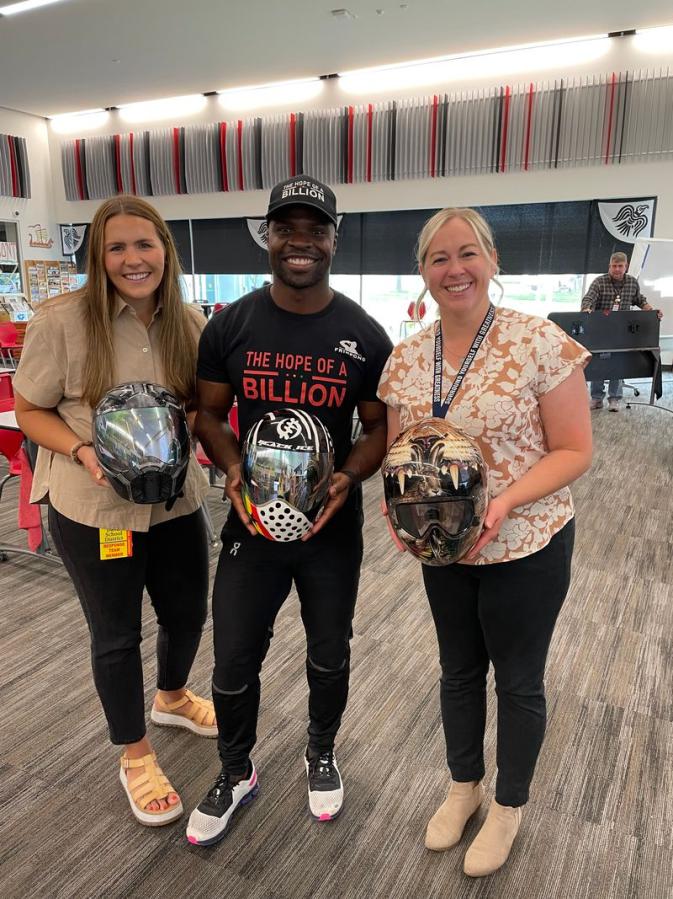 Three people holding helmets